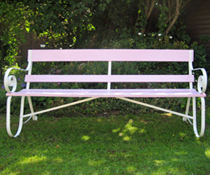 Pink coloured wrought iron and wood garden bench seat